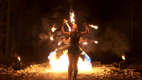 Vier-Frauen-In-Lederkleidung-Mit-Feuertanz-Und-Feuershow-Zeigen-Einen-Mann-Mit-Einem-Flammenwerfer-Im-Rücken,-Der-In-Zeitlupe-Mit-Der-Flamme-Spielt